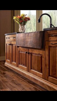 a kitchen with wooden cabinets and a large sink in it's center island, surrounded by wood flooring