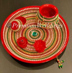 a red plate with two cups on top of it and a beaded decoration around the edge