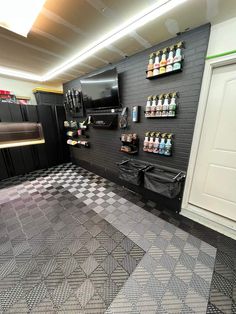 a room with black and white checkered flooring and shelves filled with drinks on the wall