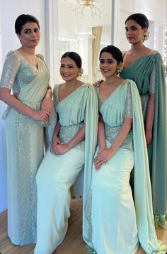 three women in dresses standing next to each other with one woman wearing an evening gown