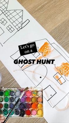 a child is painting with watercolors in front of a ghost hunt sign on a table