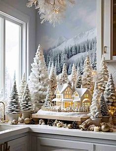 a kitchen counter topped with christmas trees and snow covered houses in the middle of it