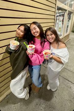 three girls standing next to each other holding ice cream