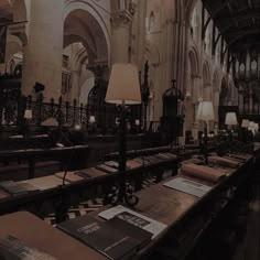 the interior of a large cathedral with many tables and lamps