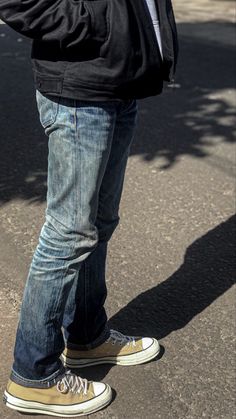 a man standing on the street with his feet up and holding something in his hand