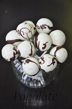 chocolate covered eggs in a glass bowl on top of a wooden table with the word propolate painted on them