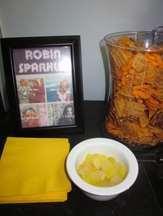 there is a bowl of food next to a framed photo and some yellow napkins