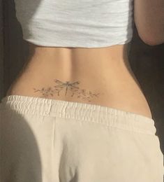 the back of a woman's stomach with a dragonfly tattoo on it