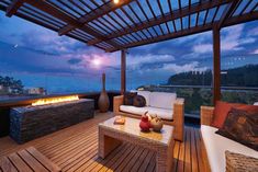 an outdoor living area with wood flooring and fire pit on the side of it