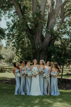 a group of women standing next to each other in front of a tree