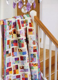 a multicolored quilt is hanging on the banister