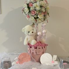 a teddy bear is sitting in a basket with flowers and other items on the table