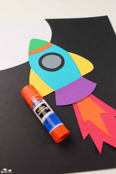 a rocket ship made out of construction paper and crayon markers on top of it