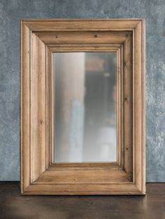 an old wooden frame with a mirror on the floor in front of a blue wall