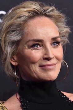 an older woman with blonde hair and blue eyes wearing black dress smiling at the camera