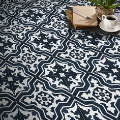 a blue and white tiled floor with a cup of coffee on it next to a potted plant