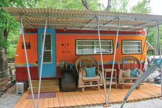 an orange and blue mobile home with chairs on the porch