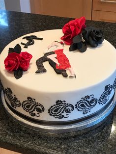 a white cake with black and red decorations on it's top, sitting on a counter