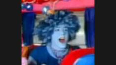 a blurry image of a woman with curly hair and blue shirt sitting in a toy car