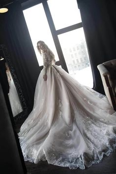 a woman standing in front of a window wearing a wedding dress