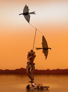 a man standing on top of a wooden floor next to a bird flying over him