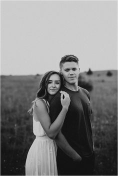 a man and woman standing next to each other in a field