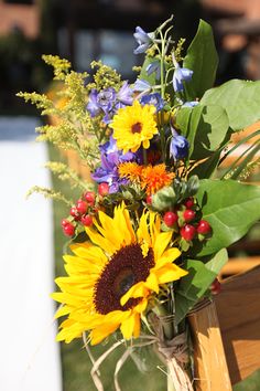 a bouquet of sunflowers and other flowers in a vase sitting on a bench