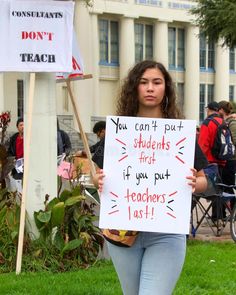 a woman holding a sign that says you can't put students first if you put teachers last