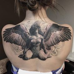 the back of a woman's neck with an angel tattoo on it