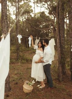 a man and woman standing next to each other in front of clothes hanging on a line