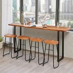 three stools are sitting at a table in front of a window with city view