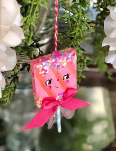 an ornament hanging from a tree decorated with pink paper and sprinkles