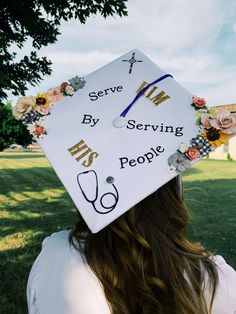 a woman wearing a white graduation cap with flowers on it and the words serve by serving people