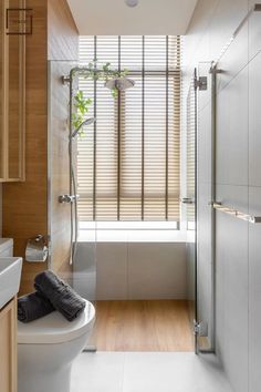 a bathroom with a toilet, sink and shower in it's center area next to a window