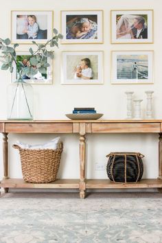 a wooden table with pictures on the wall above it and a basket next to it