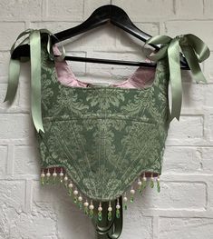 Made-to-order boned corset in sage green brocade. Embellished by hand around the hem with a combination of pink, green and freshwater pearl beading. Lace up back and tie straps fastened with satin ribbon. I would recommend sending me your measurements (last photo) so your piece can be bespoke to your size. I can also work from your trouser size, clothing size, bra size and height if necessary.  Please allow up to 4 weeks for your piece to be made and shipped. Every piece is made-to-order with lo Brocade Corset, Diy Corset, Ren Faire Outfits, Fair Outfits, Green Corset, Pearl Beading, Fairytale Fashion, Utila, Sewing Design