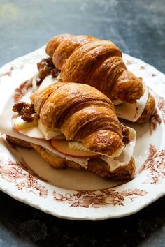 two croissants with meat and cheese on them are sitting on a plate