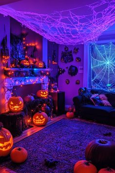 a living room decorated for halloween with purple lights and pumpkins on the fireplace mantel