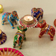 colorfully decorated elephants are standing next to each other with a candle in the middle