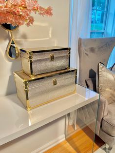 three silver suitcases sitting on top of a white table next to a gray chair