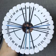 a hand holding a white and black clock with blue numbers on it's sides