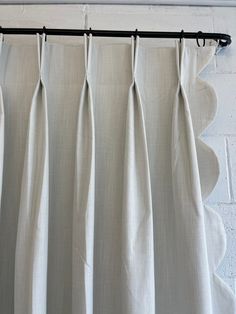 white curtains hanging on a black rod in front of a brick wall