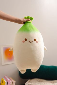 a person holding a stuffed toy in the shape of an egg with eyes and nose