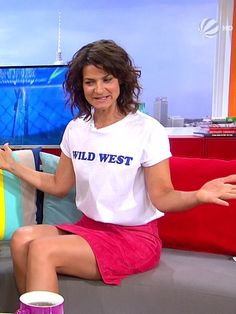 a woman sitting on top of a couch in front of a tv screen with her hands out