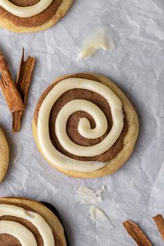 cinnamon roll cookies with white icing and cinnamon sticks on the side, surrounded by cinnamon sticks