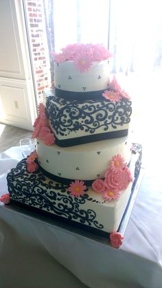 a three tiered cake with pink flowers on it sitting on top of a table