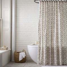 a bathroom with a tub, toilet and shower curtain that has an intricate pattern on it