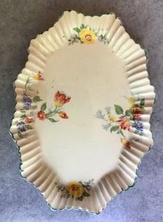 a white plate with yellow and red flowers on the rim is sitting on a gray surface