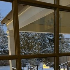 an open window looking out onto the snow covered yard and trees in the back ground