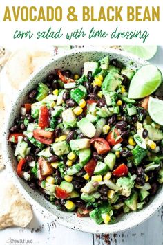 a white bowl filled with black beans, corn and avocado salad next to tortilla chips